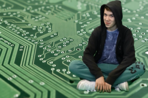 Jugendlicher sitzt vor Computerplatinen-Hintergrund