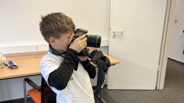 Ein Junge hält sich eine Kamera vor das Gesicht.