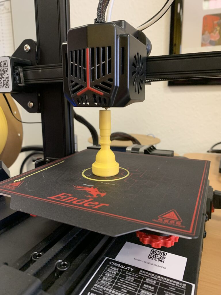 Ein 3D-Drucker druckt einen gelben Türstopper.