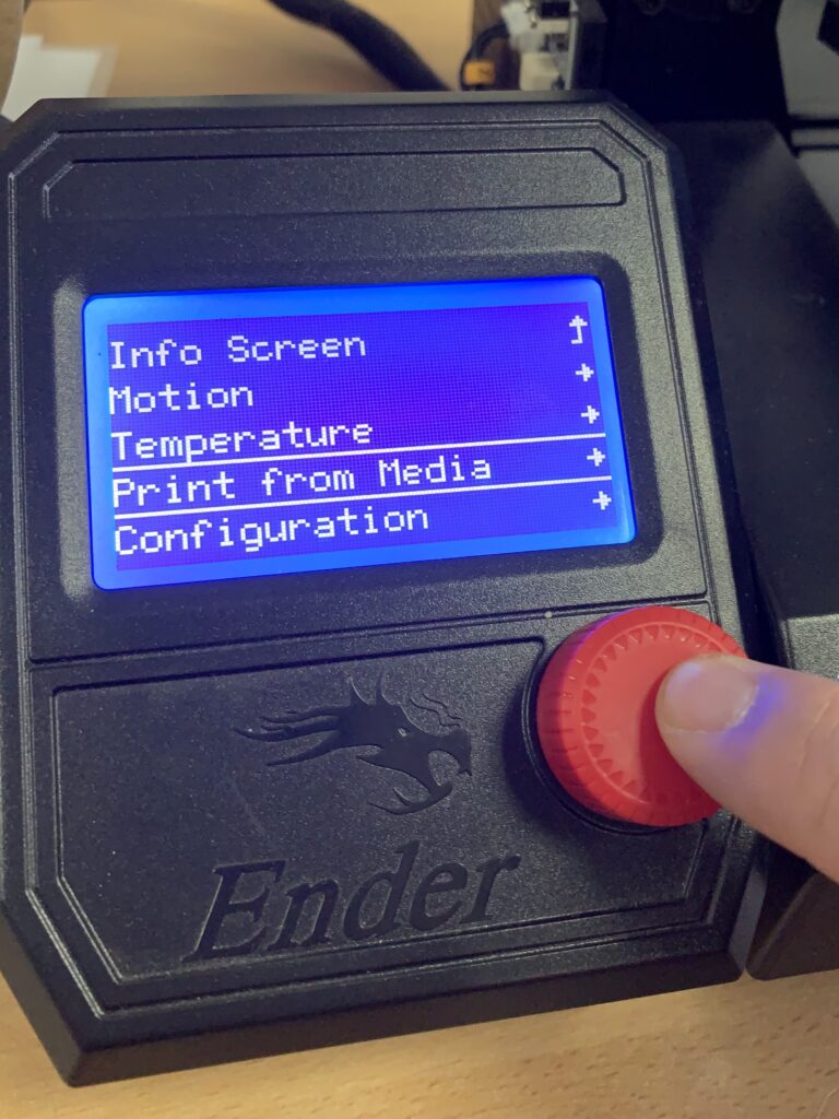Ein Finger drückt auf einen roten Knopf. Der Bildschirm von dem Gerät sagt auf Englisch "Von einem Medium drucken"