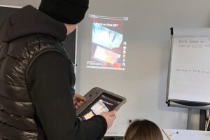 Zwei Personen schauen auf ein projiziertes TikTok-Video an der Wand