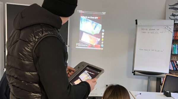 Zwei Personen schauen auf ein projiziertes TikTok-Video an der Wand