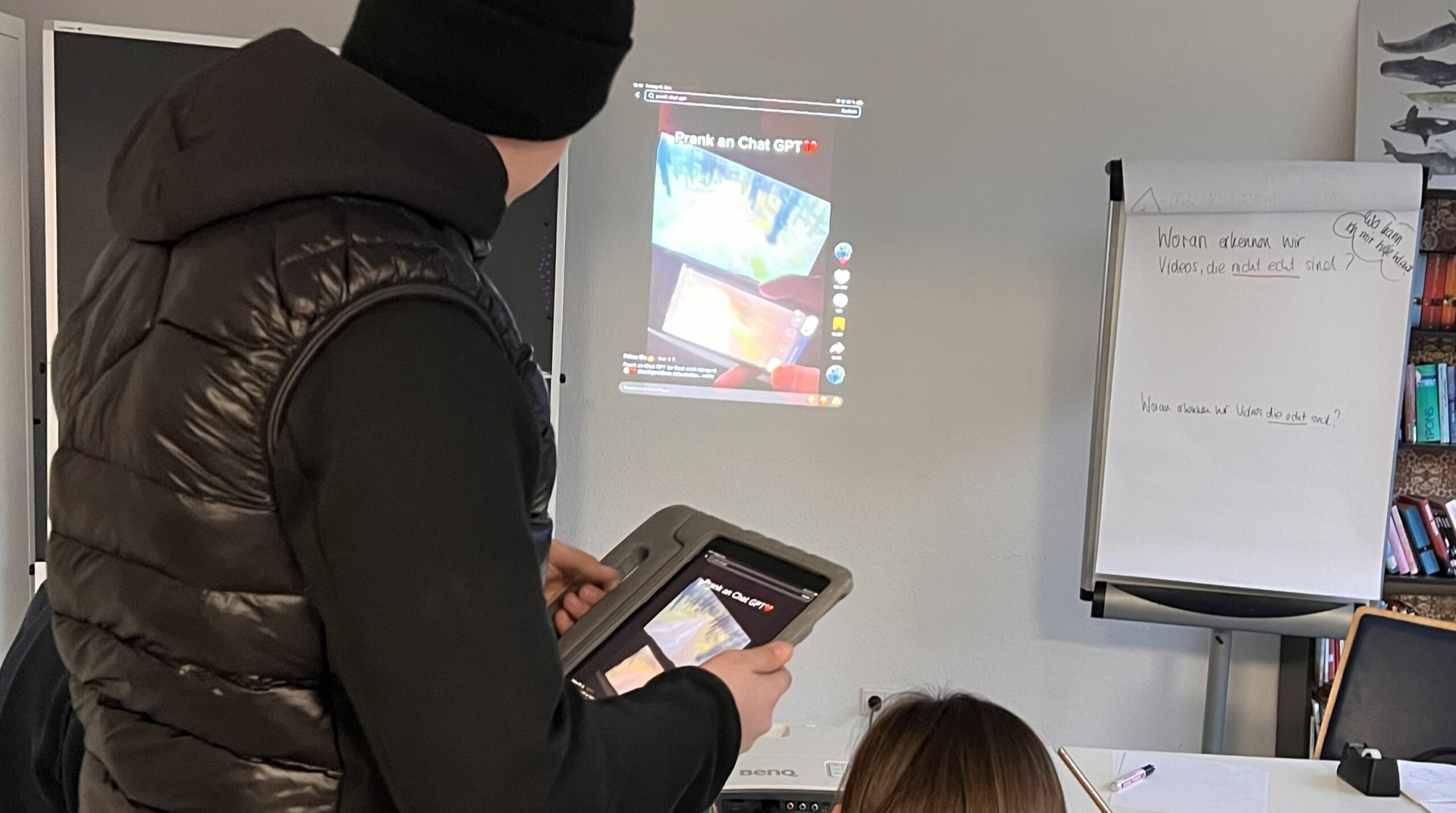 Zwei Personen schauen auf ein projiziertes TikTok-Video an der Wand